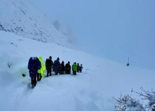 Trekkers walking on the trail to Larke Pass with snow-covered Himalayan peaks on the Manaslu Circuit Trek, Nepal.